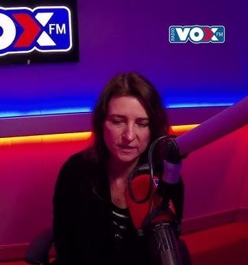 Renata Dąbkowska podczas występu na scenie, śpiewająca do mikrofonu, oświetlona dynamicznymi światłami scenicznymi.