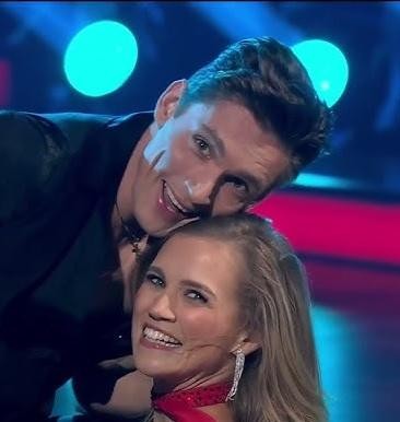 Agnieszka Kaczorowska tańcząca z partnerem w programie „Taniec z Gwiazdami”, w dynamicznej pozie na scenie.