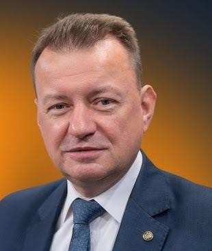 Mariusz Błaszczak jako Minister Obrony Narodowej, w otoczeniu wojskowym, symbolizujący jego rolę w kwestiach bezpieczeństwa narodowego.
