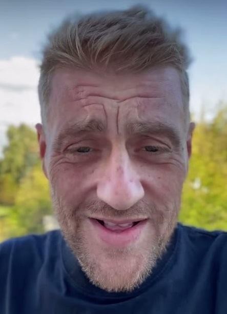 Tomasz Jakubiak, kucharz i osobowość telewizyjna, w studio nagraniowym programu kulinarnego, w kitlu szefa kuchni, z ożywioną mimiką i gestykulacją.