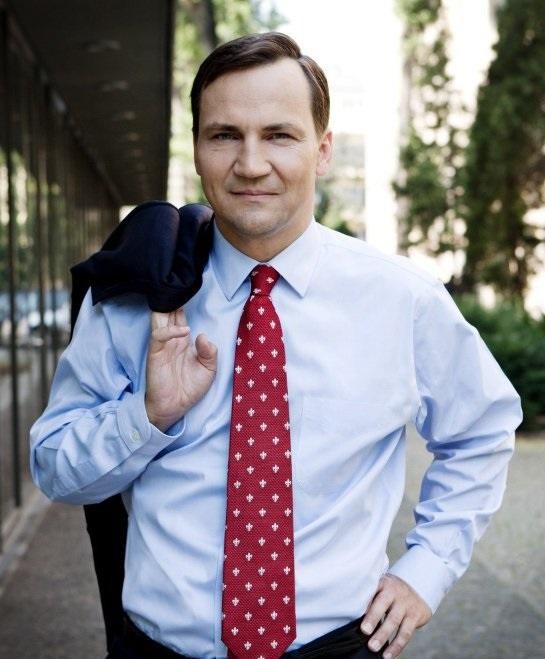 Alt: Radosław Sikorski w dyplomatycznym otoczeniu, rozmawiający lub przemawiający, symbolizujący jego aktywność w polityce zagranicznej.