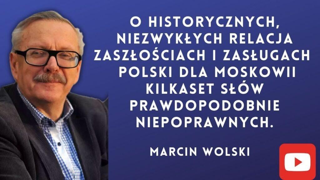 Marcin Wolski, pisarz i satyryk, uśmiechnięty, w dynamicznym zbliżeniu, z subtelnie rozmytym tłem sugerującym środowisko medialne lub twórcze.