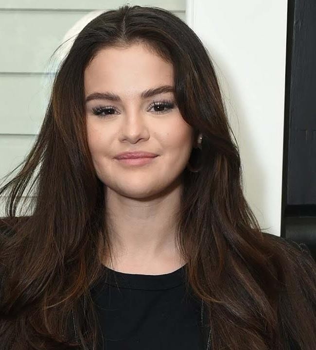 Selena Gomez na scenie podczas występu, z mikrofonem w dłoni i dynamicznym oświetleniem.